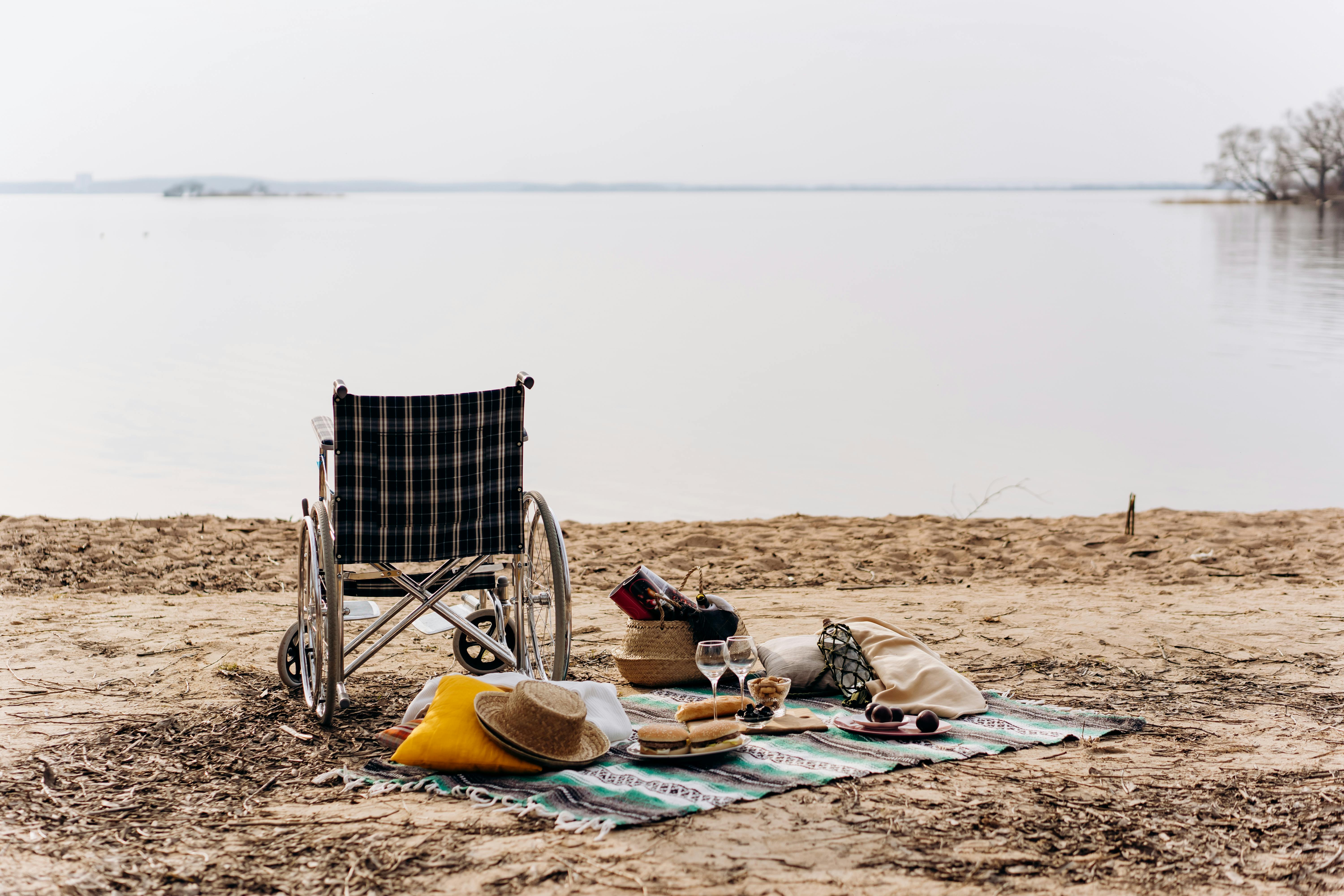 Ein Rollstuhl und eine Decke auf einen Strand, Meerblick ist zu sehen.