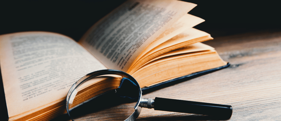 Ein Aufgeschlagenes Buch mit einer Schwarzen Lupe